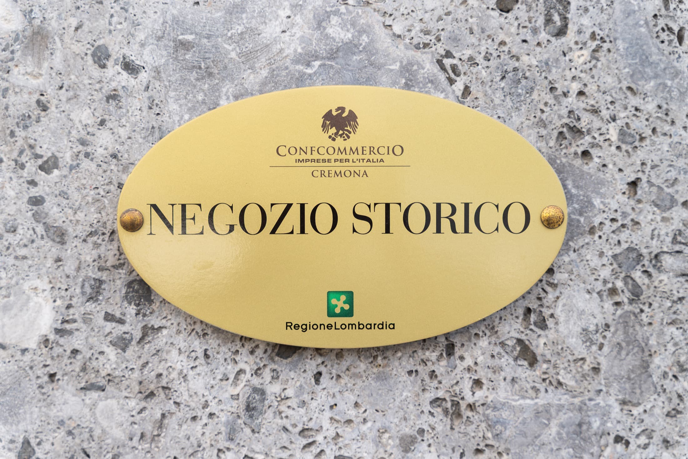 La targa di negozio storico di Confcommercio e Regione Lombardia sulla facciata della farmacia